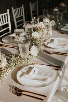 the table is set with white flowers and silverware for an elegant wedding reception or special event