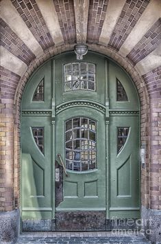 an old green door with glass panes and brick arches on the side of a building