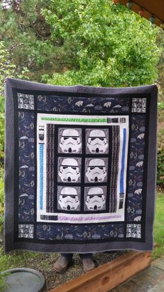 a person holding up a star wars themed quilt