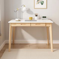 a desk with a lamp on it in front of a window and a painting hanging above