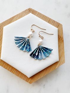 a pair of blue shell earrings on a wooden board