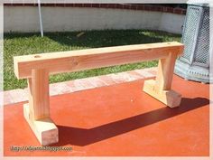 a wooden bench sitting on top of a red tile floor next to a brick wall