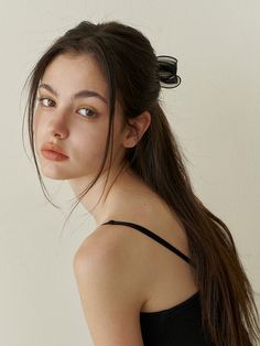 a young woman with long hair wearing a black top and looking off to the side