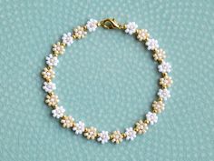 Simple beaded flower bracelet with white and light caramel colors, with gold beads between each flower. You can choose between having an extender chain or not. If you, for example, choose 16cm with extender, the bracelet will be 16cm + 3cm extender chain. The chain and clasp are 24k gold plated brass. Each jewelry item comes in a colorful envelope, as seen in the last picture, and is ready to be gifted. You can find more bracelets here https://www.etsy.com/shop/GirassolBeads?section_id=33629858 White Dainty Bracelet Jewelry, Dainty White Bracelet Jewelry, Handmade Dainty Pearl White Bracelets, White Delicate Beaded Bracelet, Dainty White Bracelet With Gold Beads, Delicate White Flower Beaded Bracelets, Delicate White Flower Shaped Beaded Bracelets, Delicate White Flower Bracelets, Delicate White Beaded Bracelets