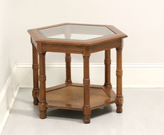 a small wooden table with glass top on the floor in front of a white wall