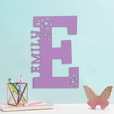 the letter e is made out of wood and has flowers on it, along with a butterfly