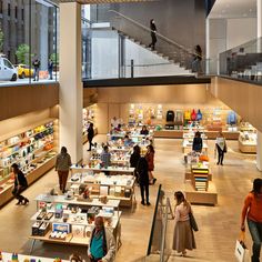 people are walking around in an open area with lots of books on tables and stairs