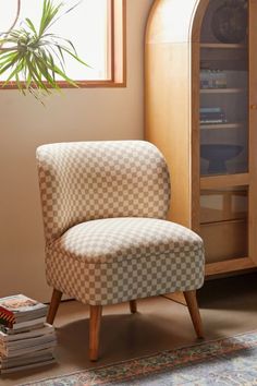 a chair sitting in front of a window next to a book shelf