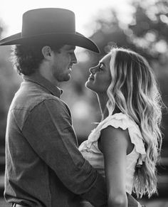 black and white photo of a man and woman in cowboy hats looking into each other's eyes