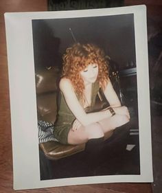 an old photo of a young woman sitting on a leather chair with her legs crossed