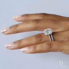 a woman's hand with a diamond ring on top of her finger and the other hand holding an engagement ring