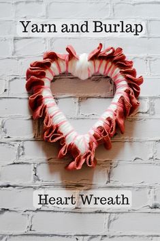 a red and white heart shaped wreath hanging on a brick wall