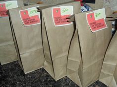 four brown paper bags with stickers on them are lined up in a row and one is empty