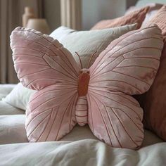 a pink butterfly pillow sitting on top of a bed