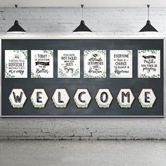 a welcome sign hanging from the side of a white brick wall next to three black lamps