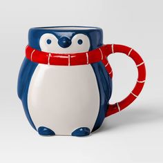 a blue and white penguin mug with a red scarf around it's neck is shown