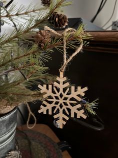 a wooden snowflake ornament hanging from a pine tree