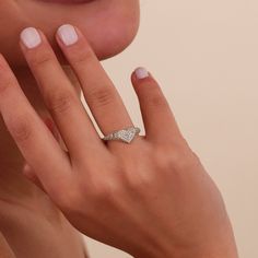 a close up of a person's hand with a ring on their finger and the other hand near her face