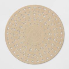 a beige round rug with small white triangles on the top and bottom, in front of a white background