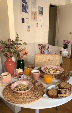 a table topped with plates and bowls filled with food next to a vase full of flowers