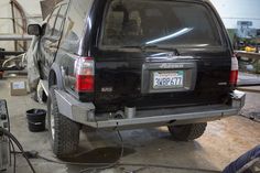 the back end of a black suv parked in a garage next to other tools and equipment