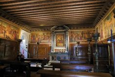 an old church with wooden pews and paintings on the walls