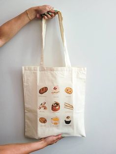 "PLEASE VISIT MY WEBSITE FOR MORE PRODUCTS! www.snapturethis.ca  The perfect lightweight reusable tote bag for coffee essentials (duh), markets, shopping, or just carrying your everyday essentials! This would make an amazing gift for a sweet treat / pastry lover! I worked with the incredible illustrator Jules (@heyoitsjules goodwellstudio)  on the original print.  Details:  Size: 15\"w x 16\"h Fabric Type: 5oz Canvas Fabric Handle: 12\" long handle Print Style: Heat Transfer  Care For Details: Hand wash cold (preferred) or cold wash on delicate cycle. DO NOT PLACE IN DRYER. Instead, let it air dry by placing it on a flat surface and realigning the straps so they don't dry wrinkled. Canvas material shrinks when you wet it, please avoid washing often and instead spot clean as needed.  How to Large Everyday Canvas Gift Bag, Daily Canvas Tote Bag For Gifts, Coffee Essentials, Pop Up Market, Gift Totes, Graphic Tote, Coffee Gifts, Reusable Grocery Bags, Bag Canvas