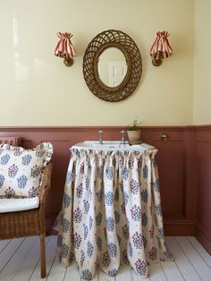 a bathroom with a sink and mirror on the wall next to a wicker chair