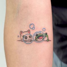 a small tattoo on the arm of a person with a cat and fish in it