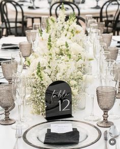 the table is set with white flowers and place settings for guests to sit down at