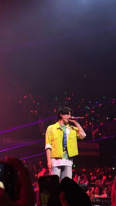 a man standing on top of a stage holding a microphone in front of an audience