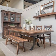 a dining room table with two benches in front of it and a mirror on the wall