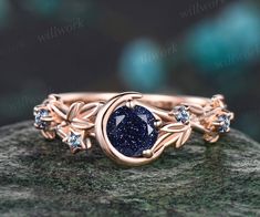 a close up view of a ring with a blue stone in the center on top of a rock