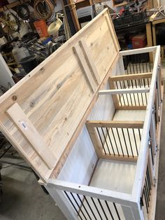 an open wooden box sitting on top of a hard wood floor in a shop filled with tools