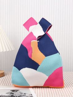 a colorful bag sitting on top of a table next to a lamp and pictures in the background