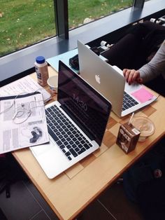 two laptops are sitting on a table with papers