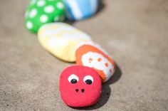 three colorful rocks with faces on them sitting in the middle of a carpeted area