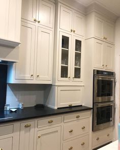 a kitchen with white cabinets, black counter tops and gold trimming on the doors