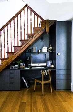 a computer on a desk under a stair case