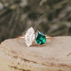 two rings with green and white stones on top of a stone slab in front of some plants