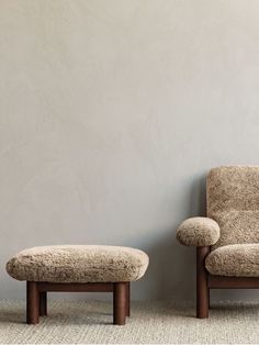 a chair and footstool sitting next to each other in front of a wall