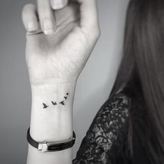 a woman's wrist tattoo with birds flying in the sky on her left arm