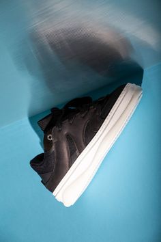 a pair of black nike shoes sitting on top of a blue floor next to a wall