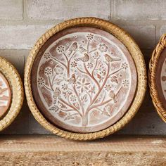 three bowls with designs on them are sitting on a shelf next to a brick wall