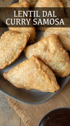 several pastries on a plate with dipping sauce in the bowl next to it and text overlay that reads lentil dal curry samsa