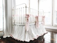 a white crib with pink ruffles and bows