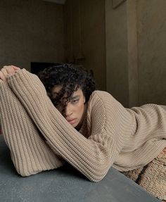 a woman laying on top of a bed wearing a sweater