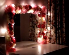 a flower mirror frame with lights in the middle and flowers on it's sides