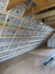 an unfinished room with wooden beams and insulation on the ceiling, walls are being built