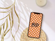 an orange and white cell phone case sitting on top of a wicker basket next to a candle